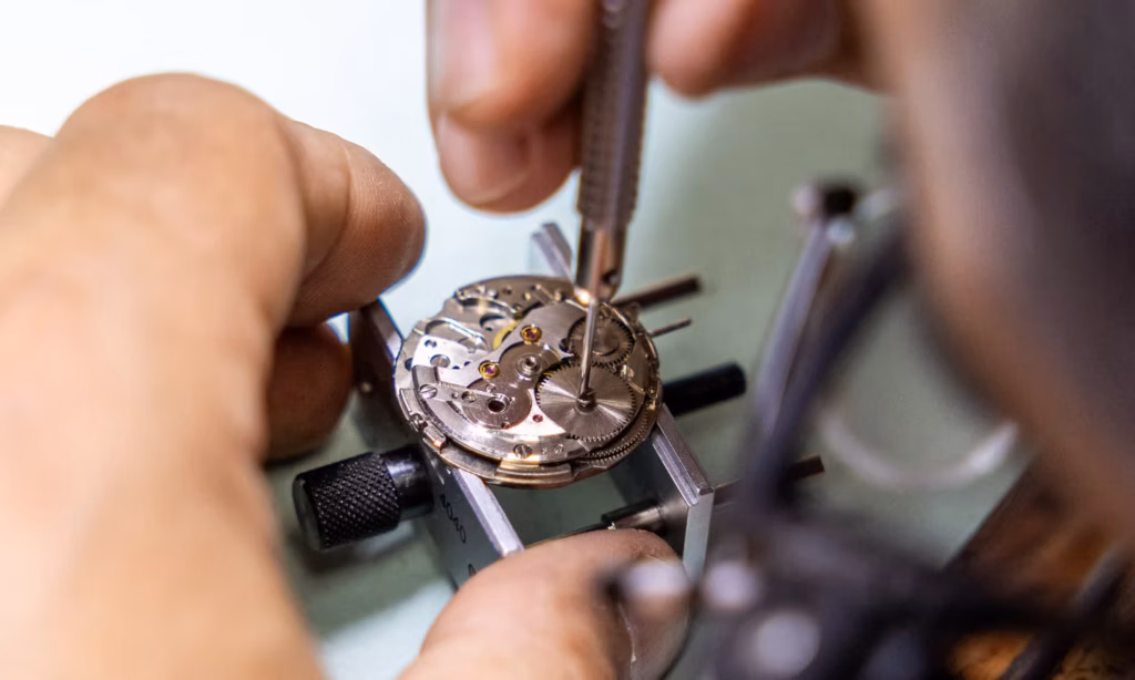 Watchmaker servicing a mechanical watch movement